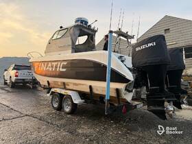 A fishing boat named 'FINATIC' is being towed on a trailer, showcasing its sleek design and powerful outboard motors, ready for a day on the water.