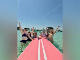 A lively group of friends celebrates together on a floating bar in crystal-clear waters, enjoying drinks and sunshine — the perfect setting for a fun day out on the water.