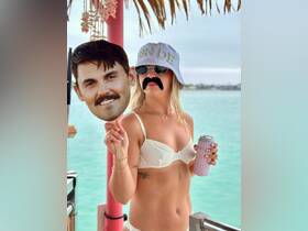 A bride-to-be enjoys a fun moment with a playful mustache and a drink, celebrating with friends in a vibrant party atmosphere — perfect for bachelorette festivities.