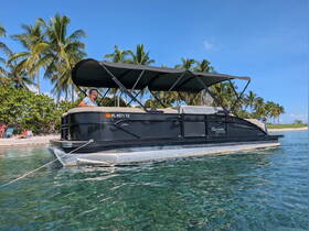 A cheerful guest enjoys the sun on a pontoon boat anchored near a beautiful beach, surrounded by palm trees — perfect for a relaxing day on the water.