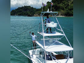 Two crew members on a fishing boat wave enthusiastically while enjoying a sunny day on the water, showcasing the excitement of a fishing adventure.