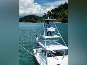 Two crew members wave from the top of a fishing boat, showcasing a vibrant day on the water surrounded by stunning coastal scenery.