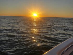 A stunning sunset over the water, captured from the deck of a boat, creating a serene and picturesque scene perfect for evening cruises.