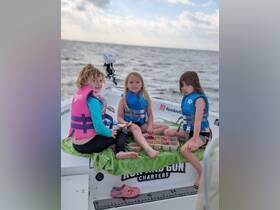 Three children enjoy snacks on the deck of a boat, showcasing a fun and safe boating experience for families.