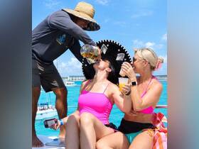 A lively scene aboard a boat as a group enjoys cocktails and fun in the sun, perfect for a festive day on the water.
