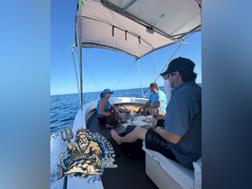 Guests relax inside a boat's cabin, enjoying a meal while surrounded by the beautiful ocean views — a perfect setting for a day on the water in Costa Rica.
