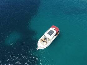 Aerial view of a boat cruising through crystal-clear waters, showcasing a relaxing day on the water with guests enjoying the sun.