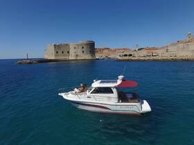 A couple relaxes on their yacht, 'My Dream', while enjoying the stunning views of Dubrovnik's historic coastline and architecture.