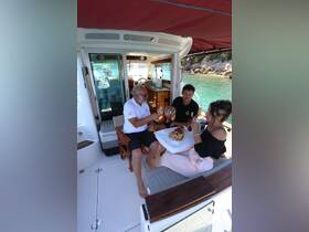Guests enjoy a meal and drinks inside the cozy cabin of a boat, showcasing a perfect setting for relaxation and dining on the water.