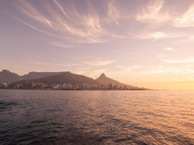 A stunning sunset view over the coastline of Cape Town, showcasing the iconic Table Mountain and vibrant city skyline — a perfect backdrop for memorable boat trips.