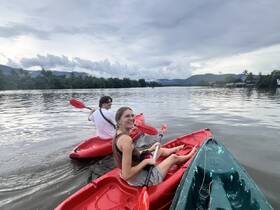 A couple enjoys kayaking on calm waters, surrounded by lush scenery — a perfect outdoor adventure for nature lovers.