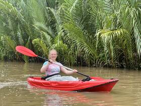 A young woman enjoys kayaking through lush greenery, showcasing the thrill of water adventures in a serene natural setting.