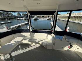 Interior view of a spacious lounge area on a boat, featuring comfortable seating and a table, perfect for relaxing while docked at the marina.