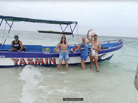 A lively group enjoys a beach day by the boat 'Yasmin,' capturing a fun moment in the water — perfect for memorable adventures and celebrations.
