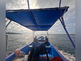 Inside view of a boat with passengers enjoying the ride, showcasing the seating and helm area under a blue canopy.