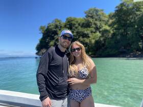 A couple enjoys a sunny day by the water, capturing a moment of joy amidst a beautiful tropical backdrop.