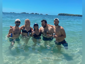A fun group of friends enjoys a sunny day in the water, celebrating with drinks in hand — the perfect beach party vibe.