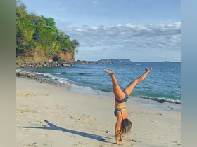 A woman performs a handstand on the beach, showcasing a fun and active moment against a picturesque coastal backdrop — perfect for beach adventures and outdoor activities.