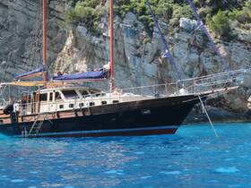 A beautiful yacht anchored in crystal-clear waters, showcasing its elegant design against a stunning rocky backdrop — perfect for luxury sailing experiences.