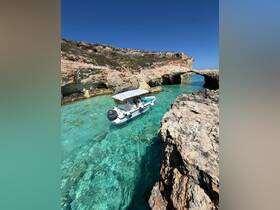 A stunning aerial view of a boat navigating through crystal-clear waters, surrounded by rocky cliffs, showcasing the beauty of the coastal landscape.