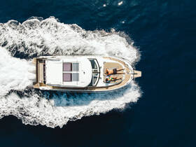 Aerial view of a couple sunbathing on a sleek boat as it glides through deep blue waters — a perfect scene for summer adventures on the sea.