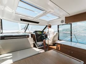 A well-designed helm area inside a boat, featuring a captain at the controls, showcasing modern amenities and a panoramic view of the water.