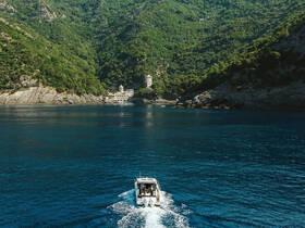 A scenic view of a boat cruising through tranquil waters, surrounded by lush greenery and rocky cliffs, showcasing the beauty of coastal exploration.