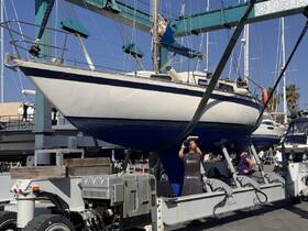 A sailboat is being serviced at the dock, showcasing the vessel's hull and maintenance activities — a glimpse into the care and upkeep of boating.