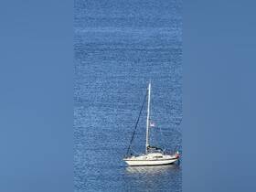 A serene view of a sailboat anchored in calm waters, showcasing the vessel's elegant design against a backdrop of deep blue sea.