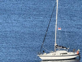 A serene view of a sailboat named 'Merak' anchored in calm waters, showcasing its elegant design against a backdrop of shimmering blue.