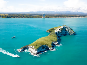 A stunning aerial view of a lush island surrounded by turquoise waters, showcasing the natural beauty of the coastline — perfect for eco tours and scenic boat trips.