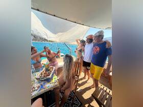 A lively group enjoys a fun boat party, capturing memories with drinks and a delicious spread of food — perfect for celebrations on the water.
