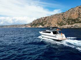 A sleek yacht cruises through the deep blue waters, showcasing its elegant design against a stunning coastal backdrop.
