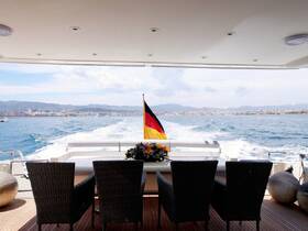 A serene view from the interior of a yacht, showcasing comfortable seating and a beautiful backdrop of the coastline as the boat glides through the water.