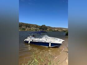 A sleek speedboat named 'Cloud 9' is docked by the shore, showcasing its stylish design against a serene backdrop of nature.