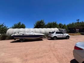 A speedboat is parked on a trailer in a sunny outdoor setting, showcasing its sleek design and readiness for the water.