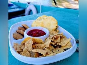 A delicious spread of snacks featuring tortilla chips, salsa, and fresh pineapple, perfect for enjoying on a boat trip.