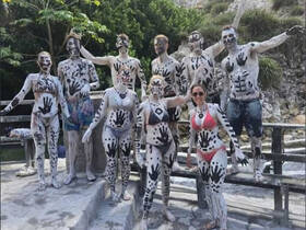 A lively group of friends celebrates with body paint, showcasing their artistic designs in a fun outdoor setting — perfect for memorable adventures and group activities.