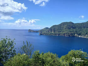 Breathtaking view of a serene coastline with lush green hills and calm blue waters, perfect for showcasing the natural beauty of the destination.