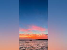 A serene sunset view featuring a sailboat silhouetted against vibrant skies, perfect for capturing the beauty of evening on the water.
