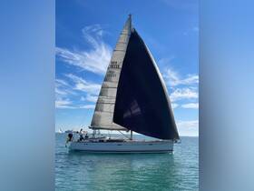 A sleek sailboat navigates through clear waters, showcasing its impressive sails against a vibrant blue sky — perfect for sailing enthusiasts and adventure seekers.