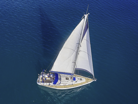 A stunning aerial view of a sailboat gracefully navigating through deep blue waters, perfect for showcasing sailing adventures and maritime experiences.