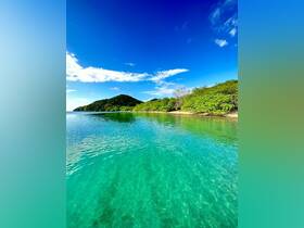 A stunning view of a tranquil coastline with crystal-clear waters and lush greenery, perfect for showcasing the beauty of island destinations.