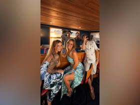 A lively group enjoys drinks and laughter aboard a boat during sunset, capturing the essence of a perfect celebration on the water.