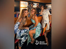 A lively group enjoys drinks and laughter aboard a boat during sunset, capturing the essence of a fun-filled evening on the water.