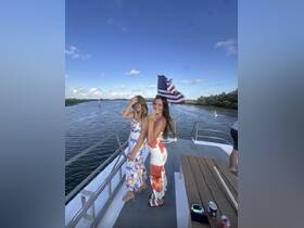 Two friends pose joyfully on the deck of a boat, enjoying a beautiful day on the water — perfect for memorable outings and celebrations.