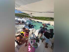A vibrant gathering on a boat with friends enjoying food and drinks, surrounded by other boats and beachgoers — a perfect day for fun in the sun.