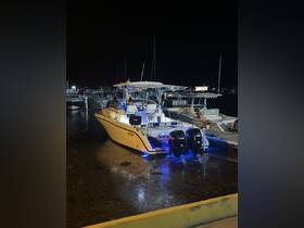A sleek speedboat named 'Century' docked at night, illuminated by blue lights, showcasing its modern design and powerful engines.