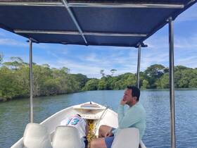 A man enjoys a serene moment on a boat surrounded by lush mangroves, perfect for exploring nature's beauty on the water.