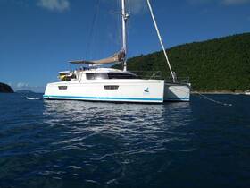 A stunning catamaran anchored in clear blue waters, showcasing its sleek design against a lush green backdrop — perfect for luxury sailing adventures.